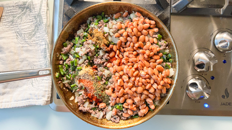 Ground beef, onions, poblano peppers, pinto beans, and spices in skillet on stovetop