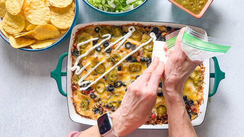 Drizzling sour cream on top of loaded beef taco casserole