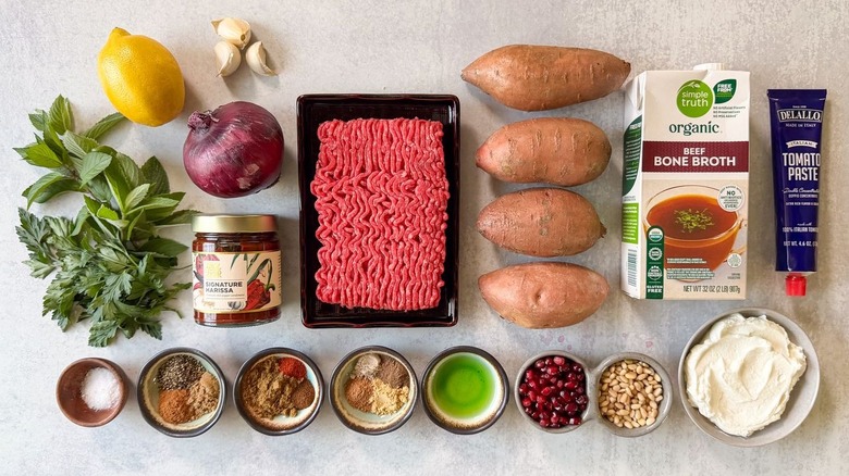 Loaded sweet potatoes with ras el hanout beef and lemon yogurt ingredients on countertop