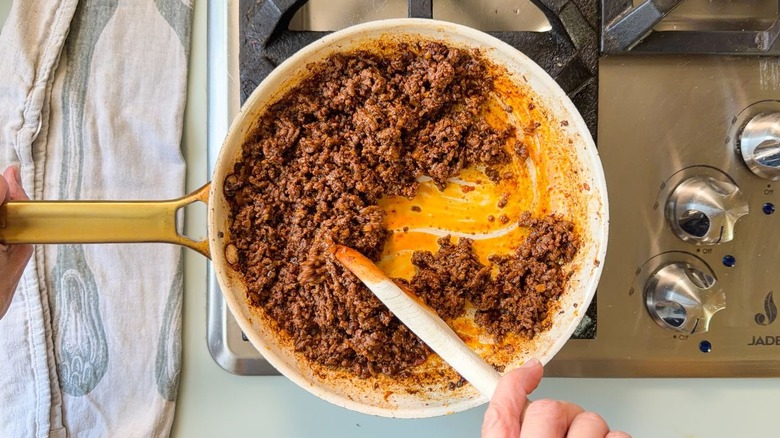 Cooking ras el hanout beef with tomato paste and harissa in skillet