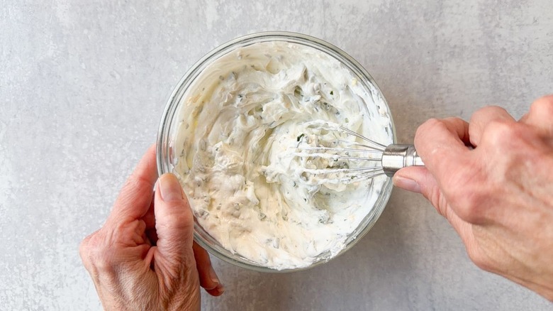 Mixing lemon yogurt sauce in glass bowl with whisk