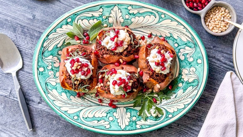 Loaded sweet potatoes with ras el hanout beef and lemon yogurt on serving platter with garnishes