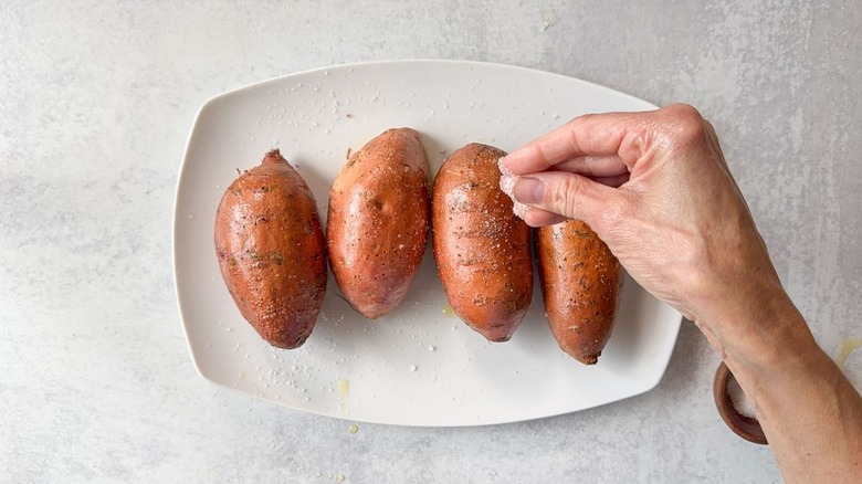 Sprinkling salt on oiled sweet potatoes on plate