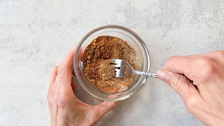 Mixing ras el hanout spices in glass bowl