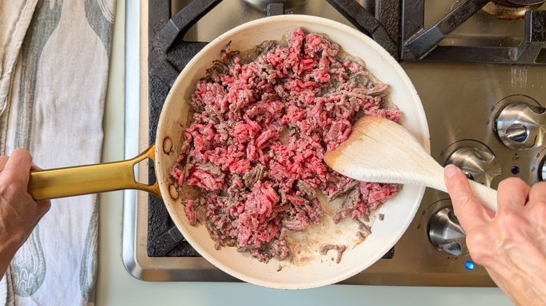 Browning ground beef in white skillet on stovetop