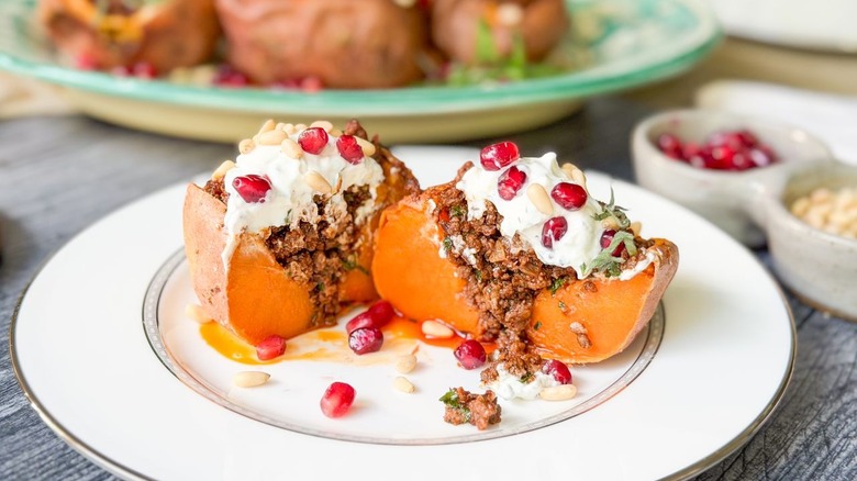 Close up of halved loaded sweet potatoes with ras el hanout beef and lemon yogurt on plate