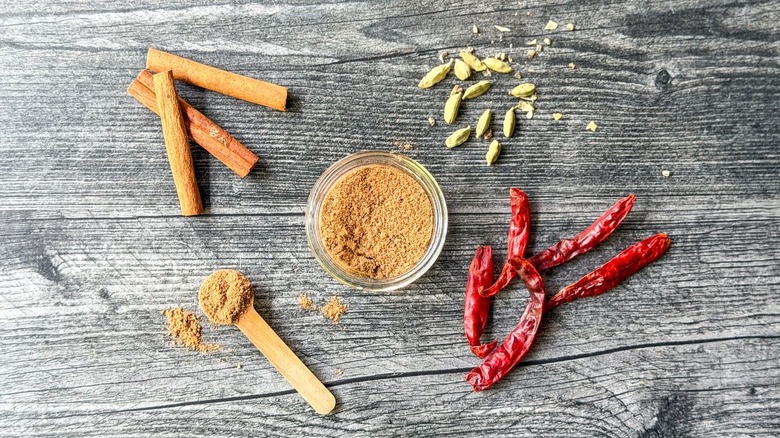 Ras el hanout spice mix in glass bowl with whole spices on the side