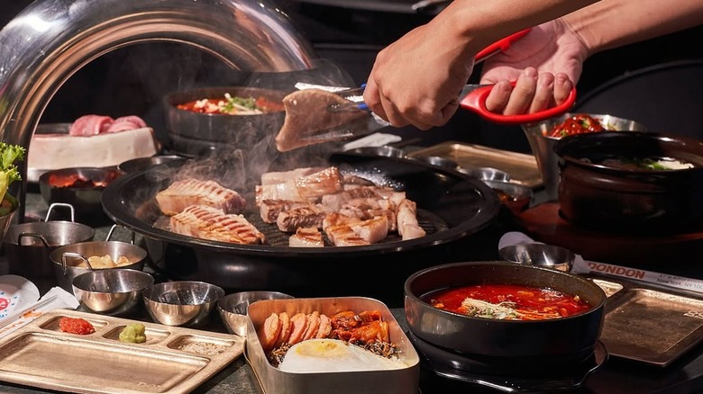 A person's hands are seen grilling Korean BBQ at Don Don in NYC.