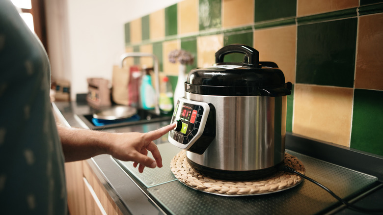 person turning on a slow cooker