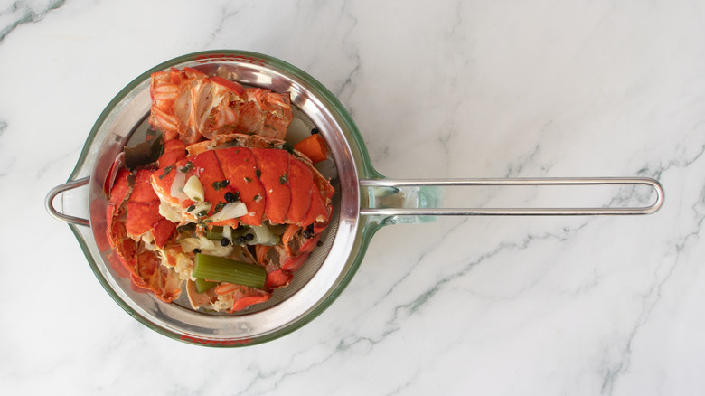 vegetables and lobster shells in a strainer