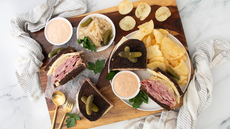 top view of sliced reuben sandwich on plate on cutting board with potato chips