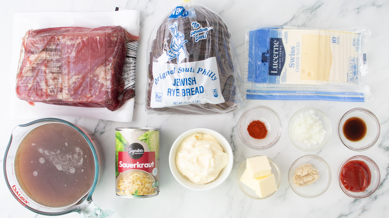 pack of corned beef, pack of Swiss cheese slices, pack of rye bread, and other reuben sandwich ingredients laid out