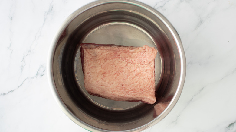aerial view of unseasoned corned beef in slow cooker pot