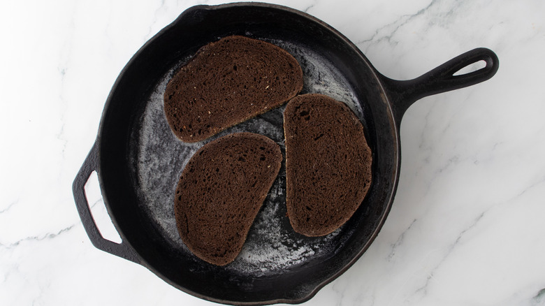 sliced bread in pan with melted butter over marble surface