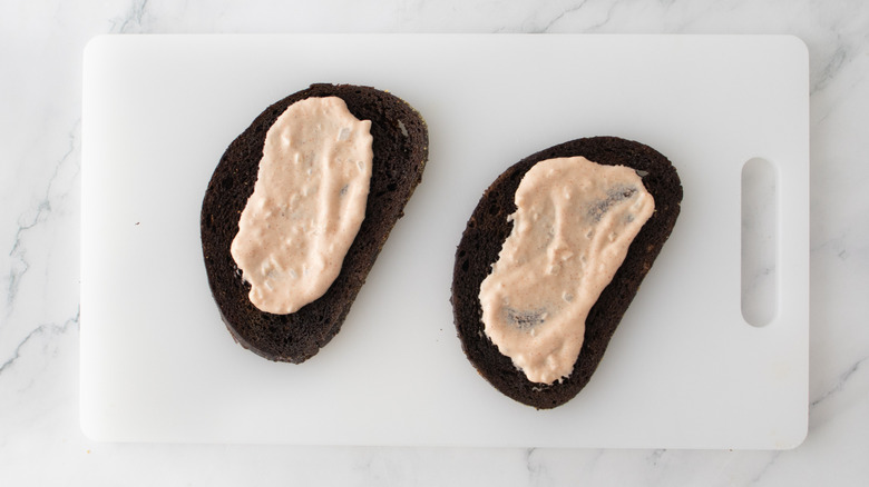 toasted bread on cutting board spread with dressing