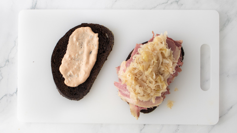 toasted bread slices with corned beef and sauerkraut on cutting board