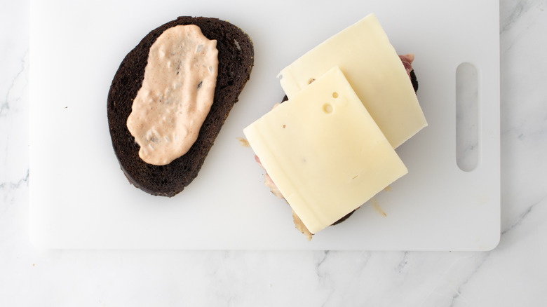 toasted bread on cutting board with cheese and dressing