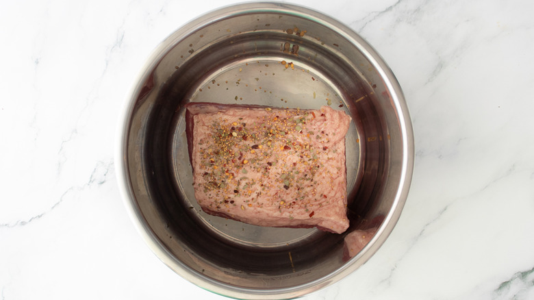 aerial view of seasoned corned beef in slow cooker pot