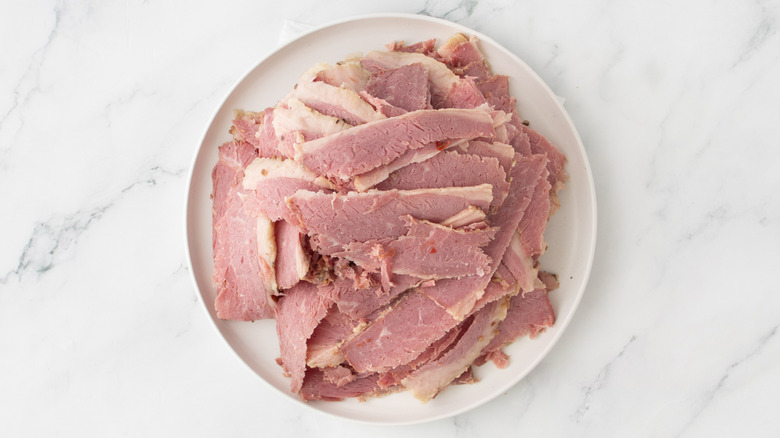 sliced corned beef piled on a white plate