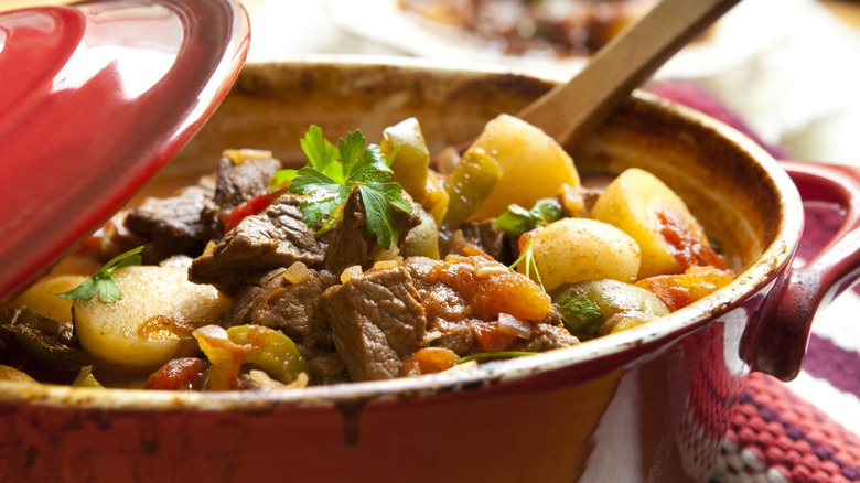 A bowl of beef stew inside a red crock pot.