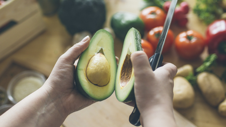 Person holding halved avocado