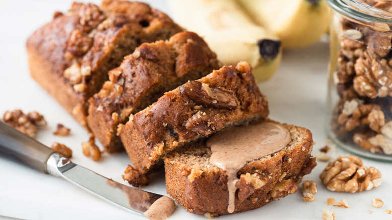 A loaf of banana bread sliced with peanut butter spread