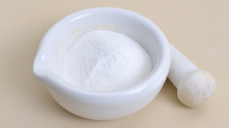 malic acid sits in a mortar with a pestle