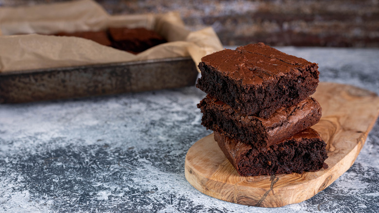 Stack of brownies near pan.