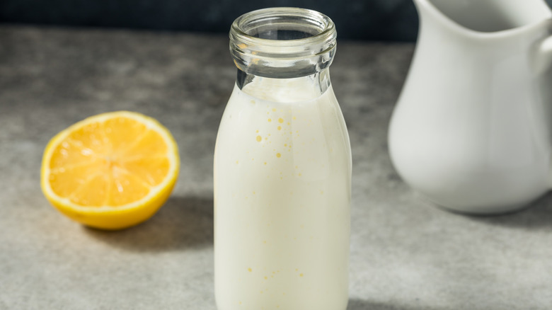 Bottle of homemade buttermilk on counter next to lemon slice.