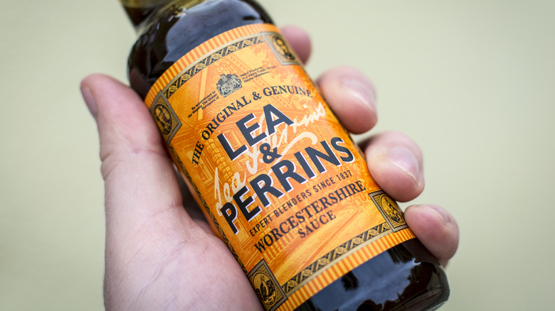 A hand holds a Worcestershire sauce bottle.