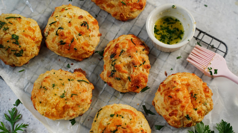 Biscuits on a wire rack with a herb butter dip and a brush on the side