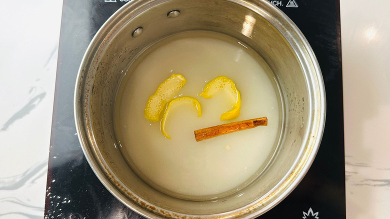 Lemon peel and cinnamon stick in sugar water in pot