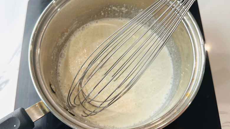 Large whisk in pot with milk