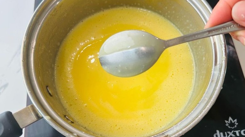 Spoon above pot with custard in it