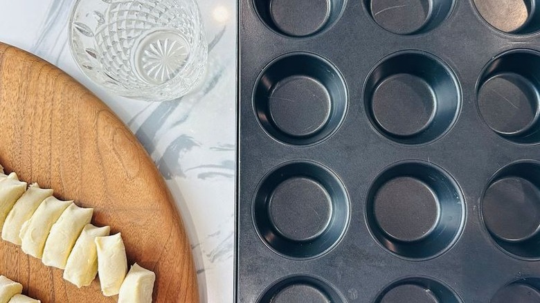 Sliced pastry dough, water cup, and muffin tin