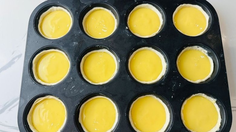 Unbaked custard tarts in muffin tin