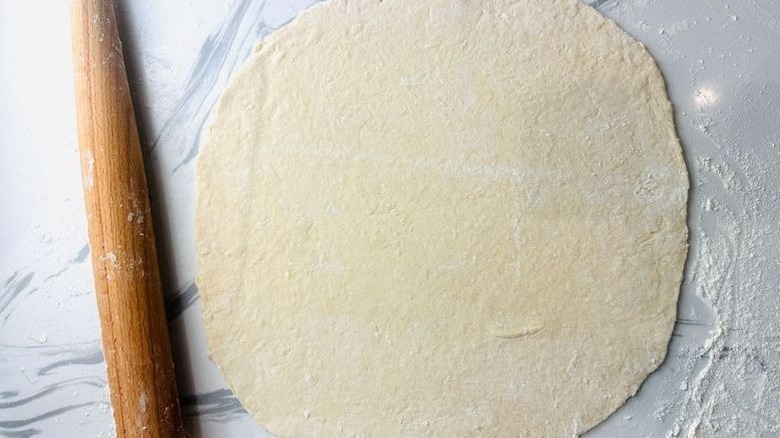 Rolled out pastry dough next to rolling pin