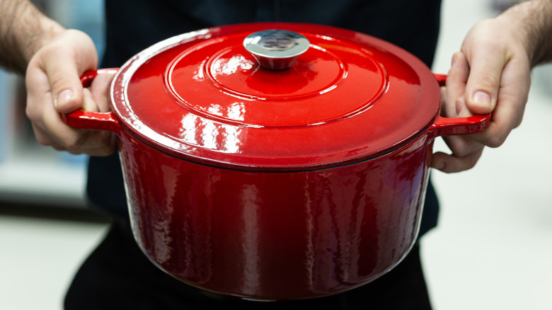man holding a red enameled dutch oven