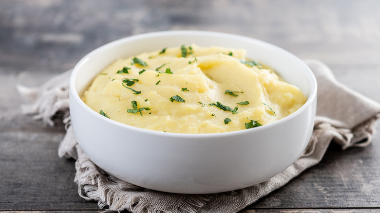 A bowl of creamy mashed potatoes on a cloth napkin.