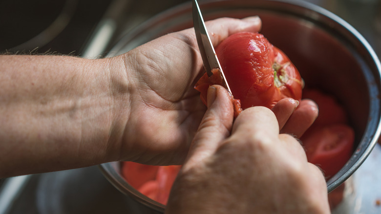 Person skinning a tomato