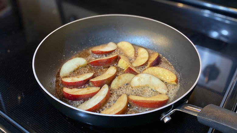 Sliced apples being cooked in a frying pan