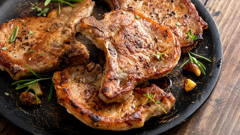 Grilled pork chops with herbs on a black plate