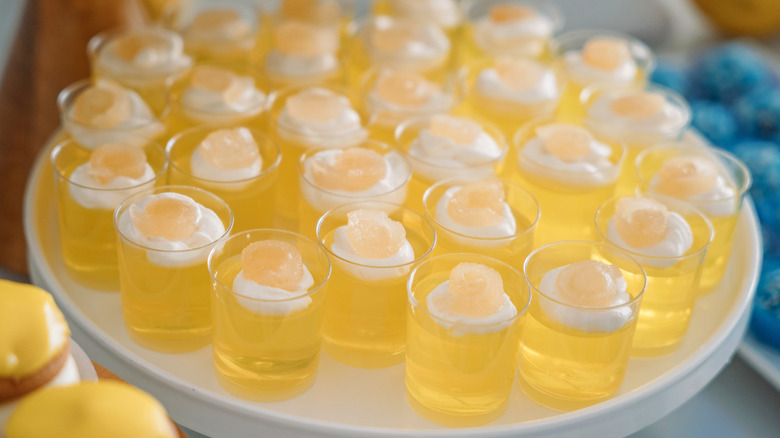 A white tray of garnished, pale yellow-hued Jell-O shots