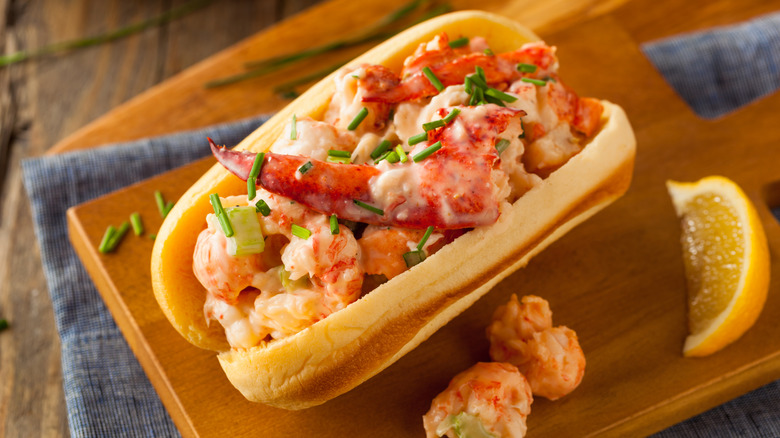 Buttery lobster roll on a wooden cutting board.