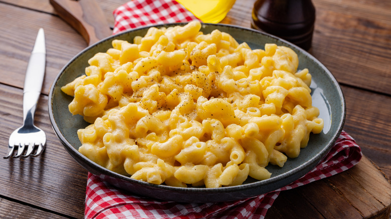 Mac and cheese served in a gray plate on top of a checkered cloth