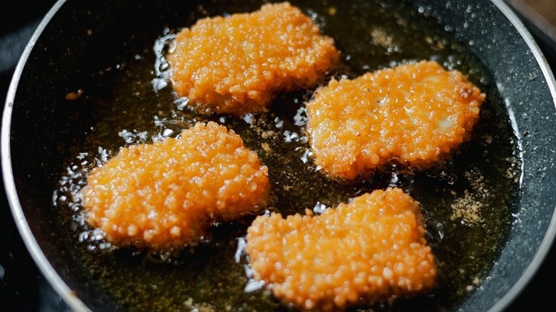 Frying homemade chicken nuggets in skillet.