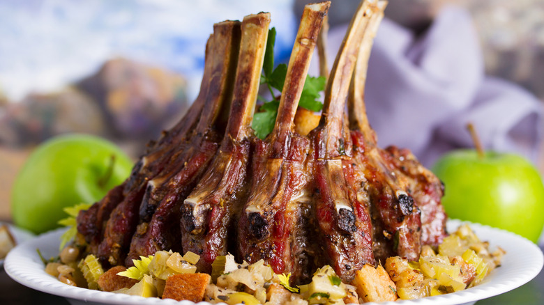 A whole crown roast is served on a white dish.