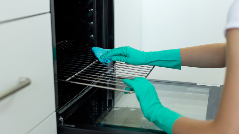 A woman cleaning a dirty oven.