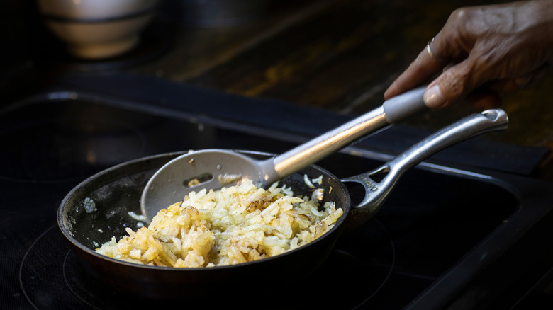 Shredded hash browns cooking in cast iron skillet