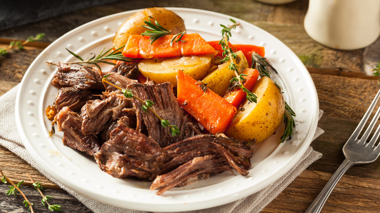 Plate of pot roast with carrots and potatoes on the side